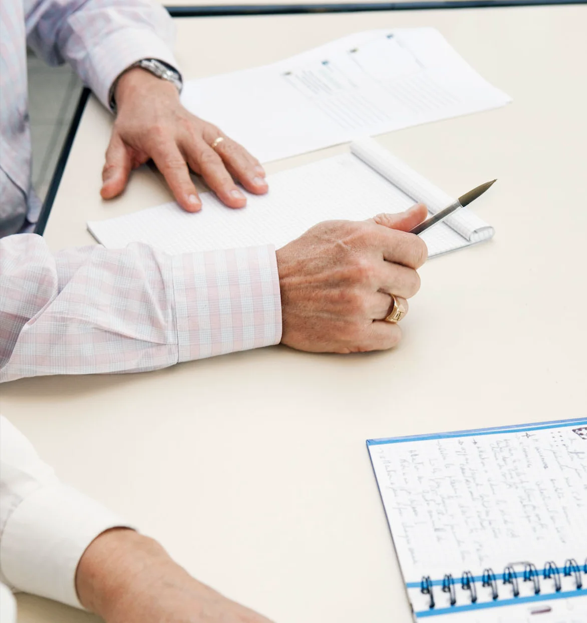 Des mains prenant des notes lors d'une réunion, symbolisant la collaboration et le partenariat avec ENOV